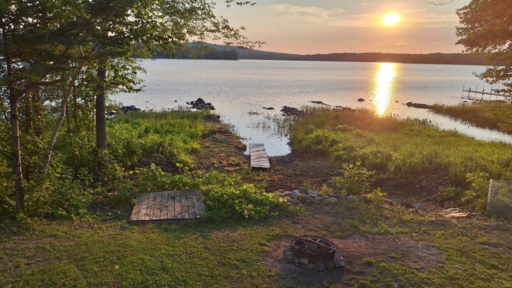 Golden sunset over Hermon Pond with small dock and fire pit